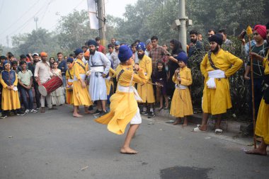 Delhi, Hindistan, 17 Kasım 2024 - Doğu Delhi bölgesinde Guru Nanak Dev, Nagar Kirtan 'ın doğum günü dolayısıyla geleneksel Nagar Kirtan, geleneksel Nagar geçit töreninde Sihler gatka ve dövüş sanatlarını sergiliyor