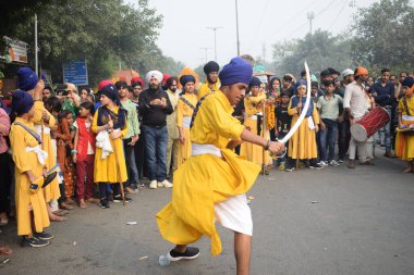 Delhi, Hindistan, 17 Kasım 2024 - Doğu Delhi bölgesinde Guru Nanak Dev, Nagar Kirtan 'ın doğum günü dolayısıyla geleneksel Nagar Kirtan, geleneksel Nagar geçit töreninde Sihler gatka ve dövüş sanatlarını sergiliyor