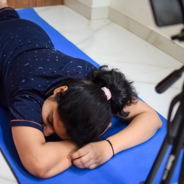 Evde yoga yapan genç Hintli bir kadın çevrimiçi yoga seansında güzel bir kız temel yoga pozisyonunda Asyalı bir kadın kapalı alanda yoga yapıyor.