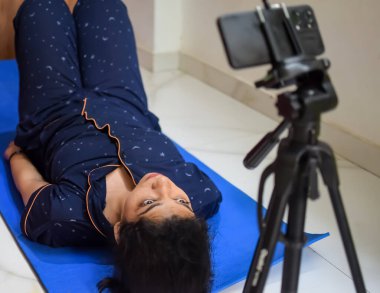 Evde yoga yapan genç Hintli bir kadın çevrimiçi yoga seansında güzel bir kız temel yoga pozisyonunda Asyalı bir kadın kapalı alanda yoga yapıyor.
