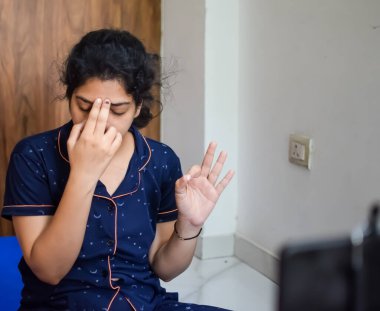 Evde yoga yapan genç Hintli bir kadın çevrimiçi yoga seansında güzel bir kız temel yoga pozisyonunda Asyalı bir kadın kapalı alanda yoga yapıyor.