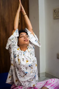 Evde yoga yapan genç Hintli bir kadın çevrimiçi yoga seansında güzel bir kız temel yoga pozisyonunda Asyalı bir kadın kapalı alanda yoga yapıyor.