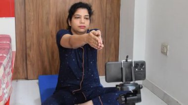 Evde yoga yapan genç Hintli bir kadın çevrimiçi yoga seansında güzel bir kız temel yoga pozisyonunda Asyalı bir kadın kapalı alanda yoga yapıyor. 