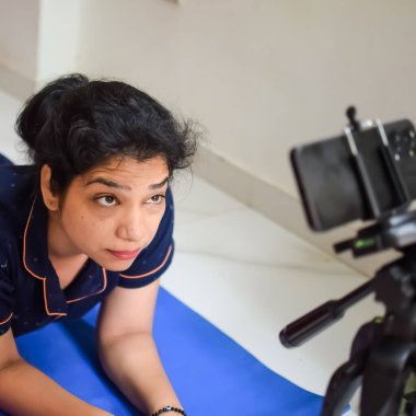 Evde yoga yapan genç Hintli bir kadın çevrimiçi yoga seansında güzel bir kız temel yoga pozisyonunda Asyalı bir kadın kapalı alanda yoga yapıyor.