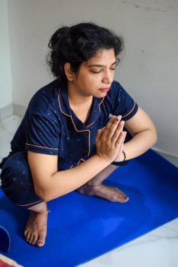 Evde yoga yapan genç Hintli bir kadın çevrimiçi yoga seansında güzel bir kız temel yoga pozisyonunda Asyalı bir kadın kapalı alanda yoga yapıyor.