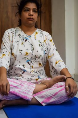 Evde yoga yapan genç Hintli bir kadın çevrimiçi yoga seansında güzel bir kız temel yoga pozisyonunda Asyalı bir kadın kapalı alanda yoga yapıyor.