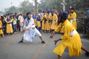 Delhi, Hindistan, 17 Kasım 2024 - Doğu Delhi bölgesinde Guru Nanak Dev, Nagar Kirtan 'ın doğum günü dolayısıyla geleneksel Nagar Kirtan, geleneksel Nagar geçit töreninde Sihler gatka ve dövüş sanatlarını sergiliyor