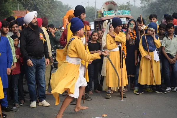 Delhi, Hindistan, 17 Kasım 2024 - Doğu Delhi bölgesinde Guru Nanak Dev, Nagar Kirtan 'ın doğum günü dolayısıyla geleneksel Nagar Kirtan, geleneksel Nagar geçit töreninde Sihler gatka ve dövüş sanatlarını sergiliyor