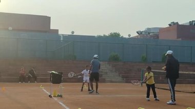 Delhi, Hindistan, 17 Şubat 2025 - Maha Open için kil tenis kortunda antrenörlük yapan genç tenisçiler, yaklaşan turnuva için küçük tenis oyuncuları antrenman yapıyor