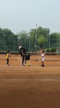 Delhi, Hindistan, 17 Şubat 2025 - Maha Open için kil tenis kortunda antrenörlük yapan genç tenisçiler, yaklaşan turnuva için küçük tenis oyuncuları antrenman yapıyor