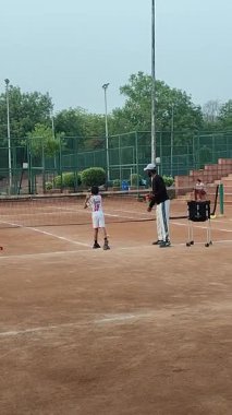 Delhi, Hindistan, 17 Şubat 2025 - Maha Open için kil tenis kortunda antrenörlük yapan genç tenisçiler, yaklaşan turnuva için küçük tenis oyuncuları antrenman yapıyor