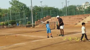Delhi, Hindistan, 17 Şubat 2025 - Maha Open için kil tenis kortunda antrenörlük yapan genç tenisçiler, yaklaşan turnuva için küçük tenis oyuncuları antrenman yapıyor