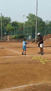 Delhi, Hindistan, 17 Şubat 2025 - Maha Open için kil tenis kortunda antrenörlük yapan genç tenisçiler, yaklaşan turnuva için küçük tenis oyuncuları antrenman yapıyor