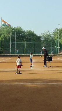Delhi, Hindistan, 17 Şubat 2025 - Maha Open için kil tenis kortunda antrenörlük yapan genç tenisçiler, yaklaşan turnuva için küçük tenis oyuncuları antrenman yapıyor