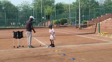 Delhi, Hindistan, 17 Şubat 2025 - Maha Open için kil tenis kortunda antrenörlük yapan genç tenisçiler, yaklaşan turnuva için küçük tenis oyuncuları antrenman yapıyor