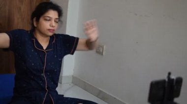 Evde yoga yapan genç Hintli bir kadın çevrimiçi yoga seansında güzel bir kız temel yoga pozisyonunda Asyalı bir kadın kapalı alanda yoga yapıyor. 