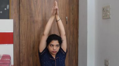 Evde yoga yapan genç Hintli bir kadın çevrimiçi yoga seansında güzel bir kız temel yoga pozisyonunda Asyalı bir kadın kapalı alanda yoga yapıyor. 