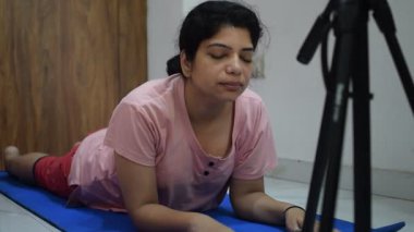 Evde yoga yapan genç Hintli bir kadın çevrimiçi yoga seansında güzel bir kız temel yoga pozisyonunda Asyalı bir kadın kapalı alanda yoga yapıyor. 