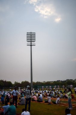 Yeni Delhi, Hindistan, 21 Haziran 2024 - Uluslararası Yoga Günü 'nde Delhi' deki Yamuna Spor Kompleksi 'nde grup Yoga egzersiz oturumu, kriket stadyumunda yoga sınıfına katılan büyük bir grup yetişkin