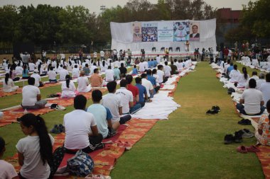 Yeni Delhi, Hindistan, 21 Haziran 2024 - Uluslararası Yoga Günü 'nde Delhi' deki Yamuna Spor Kompleksi 'nde grup Yoga egzersiz oturumu, kriket stadyumunda yoga sınıfına katılan büyük bir grup yetişkin