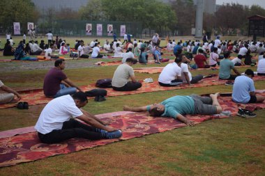 Yeni Delhi, Hindistan, 21 Haziran 2024 - Uluslararası Yoga Günü 'nde Delhi' deki Yamuna Spor Kompleksi 'nde grup Yoga egzersiz oturumu, kriket stadyumunda yoga sınıfına katılan büyük bir grup yetişkin