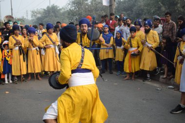 Delhi, Hindistan, 17 Kasım 2024 - Doğu Delhi bölgesinde Guru Nanak Dev, Nagar Kirtan 'ın doğum günü dolayısıyla geleneksel Nagar Kirtan, geleneksel Nagar geçit töreninde Sihler gatka ve dövüş sanatlarını sergiliyor