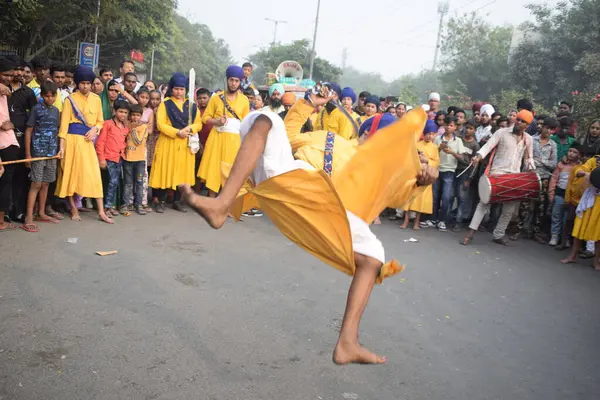 Delhi, Hindistan, 17 Kasım 2024 - Doğu Delhi bölgesinde Guru Nanak Dev, Nagar Kirtan 'ın doğum günü dolayısıyla geleneksel Nagar Kirtan, geleneksel Nagar geçit töreninde Sihler gatka ve dövüş sanatlarını sergiliyor