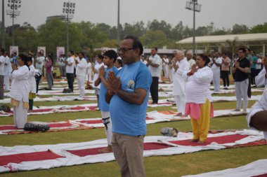 Yeni Delhi, Hindistan, 21 Haziran 2024 - Uluslararası Yoga Günü 'nde Delhi' deki Yamuna Spor Kompleksi 'nde grup Yoga egzersiz oturumu, kriket stadyumunda yoga sınıfına katılan büyük bir grup yetişkin