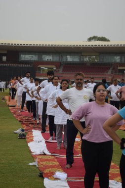 Yeni Delhi, Hindistan, 21 Haziran 2024 - Uluslararası Yoga Günü 'nde Delhi' deki Yamuna Spor Kompleksi 'nde grup Yoga egzersiz oturumu, kriket stadyumunda yoga sınıfına katılan büyük bir grup yetişkin