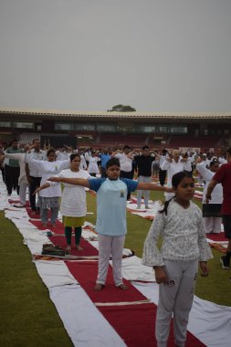 Yeni Delhi, Hindistan, 21 Haziran 2024 - Uluslararası Yoga Günü 'nde Delhi' deki Yamuna Spor Kompleksi 'nde grup Yoga egzersiz oturumu, kriket stadyumunda yoga sınıfına katılan büyük bir grup yetişkin