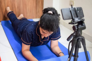 Evde yoga yapan genç Hintli bir kadın çevrimiçi yoga seansında güzel bir kız temel yoga pozisyonunda Asyalı bir kadın kapalı alanda yoga yapıyor.