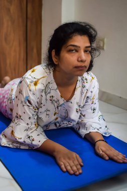 Evde yoga yapan genç Hintli bir kadın çevrimiçi yoga seansında güzel bir kız temel yoga pozisyonunda Asyalı bir kadın kapalı alanda yoga yapıyor.