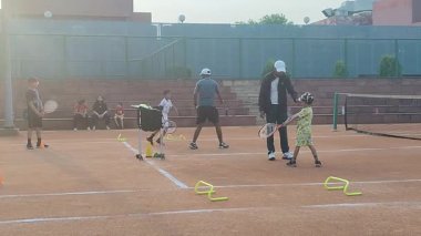 Delhi, Hindistan, 17 Şubat 2025 - Maha Open için kil tenis kortunda antrenörlük yapan genç tenisçiler, yaklaşan turnuva için küçük tenis oyuncuları antrenman yapıyor