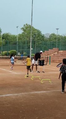 Delhi, Hindistan, 17 Şubat 2025 - Maha Open için kil tenis kortunda antrenörlük yapan genç tenisçiler, yaklaşan turnuva için küçük tenis oyuncuları antrenman yapıyor