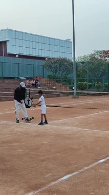 Delhi, Hindistan, 17 Şubat 2025 - Maha Open için kil tenis kortunda antrenörlük yapan genç tenisçiler, yaklaşan turnuva için küçük tenis oyuncuları antrenman yapıyor
