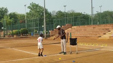 Delhi, Hindistan, 17 Şubat 2025 - Maha Open için kil tenis kortunda antrenörlük yapan genç tenisçiler, yaklaşan turnuva için küçük tenis oyuncuları antrenman yapıyor