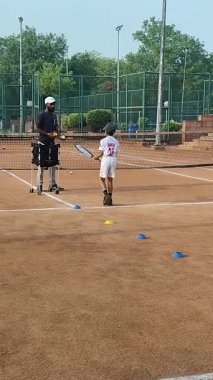 Delhi, Hindistan, 17 Şubat 2025 - Maha Open için kil tenis kortunda antrenörlük yapan genç tenisçiler, yaklaşan turnuva için küçük tenis oyuncuları antrenman yapıyor
