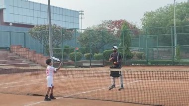 Delhi, Hindistan, 17 Şubat 2025 - Maha Open için kil tenis kortunda antrenörlük yapan genç tenisçiler, yaklaşan turnuva için küçük tenis oyuncuları antrenman yapıyor
