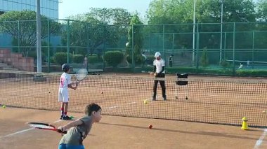 Delhi, Hindistan, 17 Şubat 2025 - Maha Open için kil tenis kortunda antrenörlük yapan genç tenisçiler, yaklaşan turnuva için küçük tenis oyuncuları antrenman yapıyor