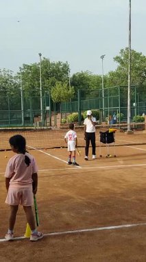 Delhi, Hindistan, 17 Şubat 2025 - Maha Open için kil tenis kortunda antrenörlük yapan genç tenisçiler, yaklaşan turnuva için küçük tenis oyuncuları antrenman yapıyor