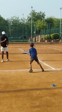 Delhi, Hindistan, 17 Şubat 2025 - Maha Open için kil tenis kortunda antrenörlük yapan genç tenisçiler, yaklaşan turnuva için küçük tenis oyuncuları antrenman yapıyor