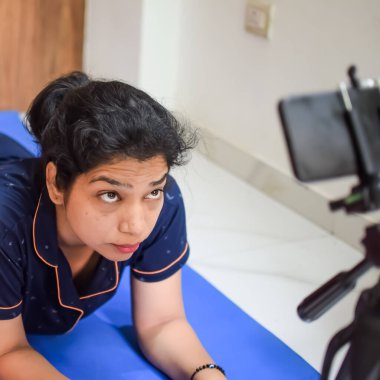 Evde yoga yapan genç Hintli bir kadın çevrimiçi yoga seansında güzel bir kız temel yoga pozisyonunda Asyalı bir kadın kapalı alanda yoga yapıyor.