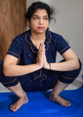 Evde yoga yapan genç Hintli bir kadın çevrimiçi yoga seansında güzel bir kız temel yoga pozisyonunda Asyalı bir kadın kapalı alanda yoga yapıyor.