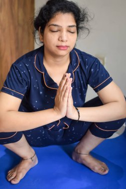 Evde yoga yapan genç Hintli bir kadın çevrimiçi yoga seansında güzel bir kız temel yoga pozisyonunda Asyalı bir kadın kapalı alanda yoga yapıyor.