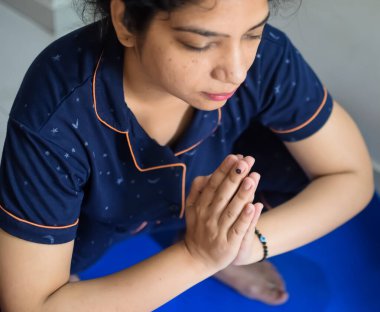 Evde yoga yapan genç Hintli bir kadın çevrimiçi yoga seansında güzel bir kız temel yoga pozisyonunda Asyalı bir kadın kapalı alanda yoga yapıyor.