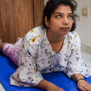 Evde yoga yapan genç Hintli bir kadın çevrimiçi yoga seansında güzel bir kız temel yoga pozisyonunda Asyalı bir kadın kapalı alanda yoga yapıyor.