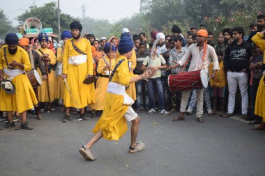Delhi, Hindistan, 17 Kasım 2024 - Doğu Delhi bölgesinde Guru Nanak Dev, Nagar Kirtan 'ın doğum günü dolayısıyla geleneksel Nagar Kirtan, geleneksel Nagar geçit töreninde Sihler gatka ve dövüş sanatlarını sergiliyor