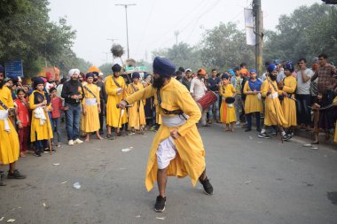 Delhi, Hindistan, 17 Kasım 2024 - Doğu Delhi bölgesinde Guru Nanak Dev, Nagar Kirtan 'ın doğum günü dolayısıyla geleneksel Nagar Kirtan, geleneksel Nagar geçit töreninde Sihler gatka ve dövüş sanatlarını sergiliyor