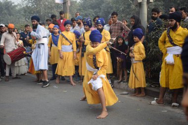 Delhi, Hindistan, 17 Kasım 2024 - Doğu Delhi bölgesinde Guru Nanak Dev, Nagar Kirtan 'ın doğum günü dolayısıyla geleneksel Nagar Kirtan, geleneksel Nagar geçit töreninde Sihler gatka ve dövüş sanatlarını sergiliyor