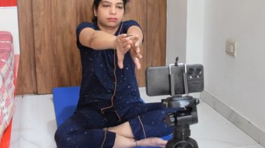 Evde yoga yapan genç Hintli bir kadın çevrimiçi yoga seansında güzel bir kız temel yoga pozisyonunda Asyalı bir kadın kapalı alanda yoga yapıyor. 